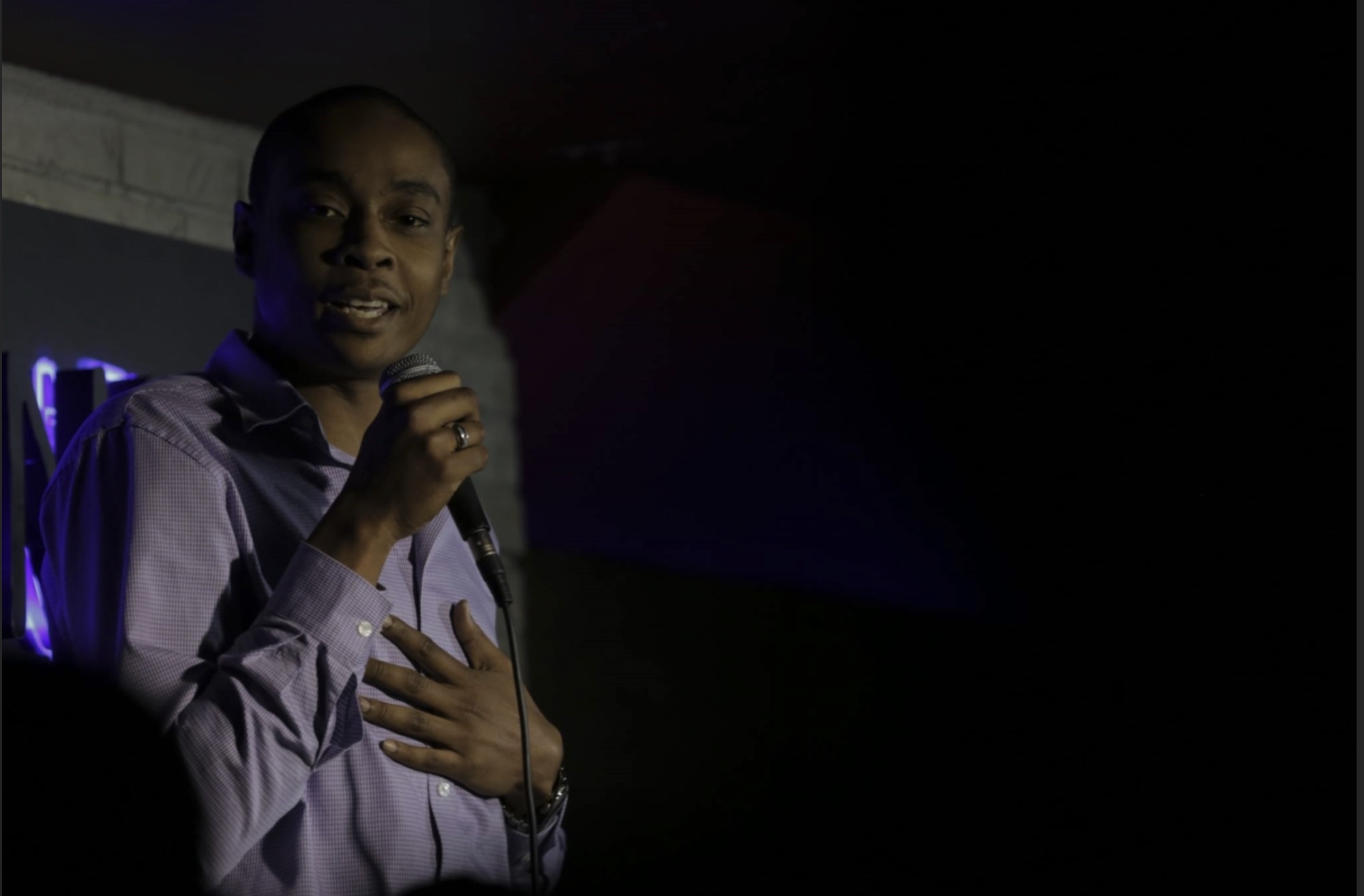 Kenan performing standup comedy with a microphone in hand